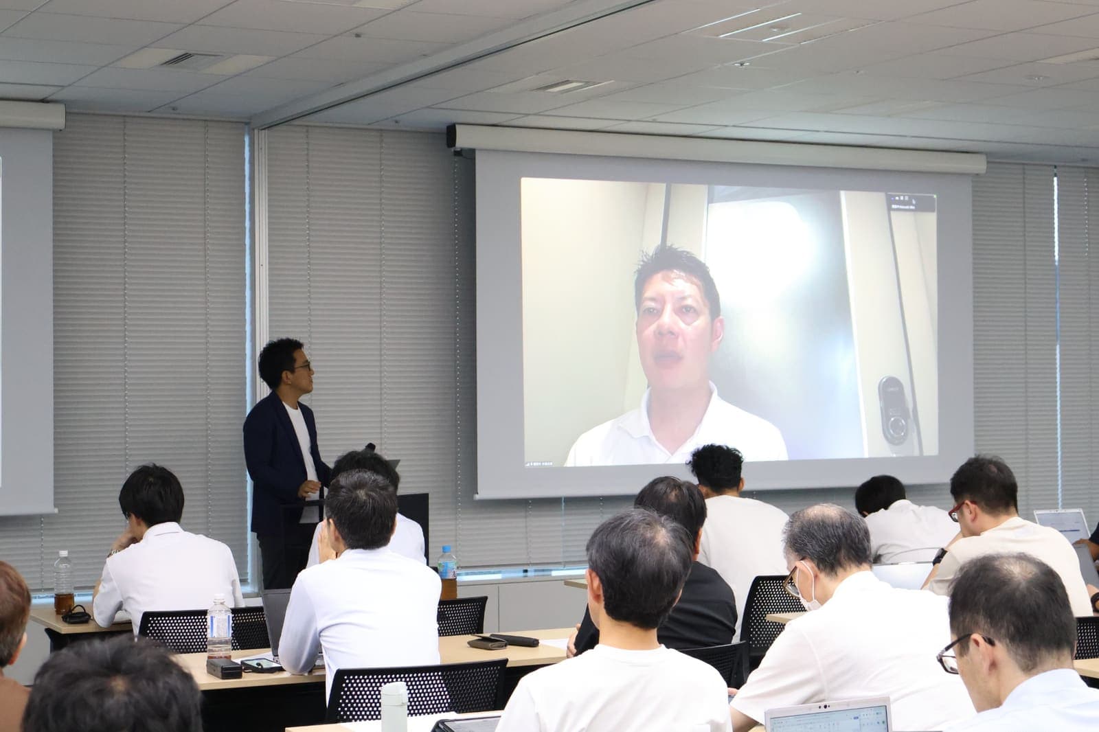オンライン登壇する磐田市の草地博昭市長と会場の宇都宮竜司